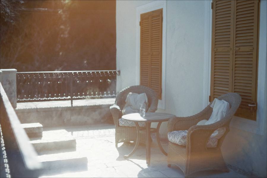 Twee lege rieten stoelen met een klein tafeltje op een zonnig terras